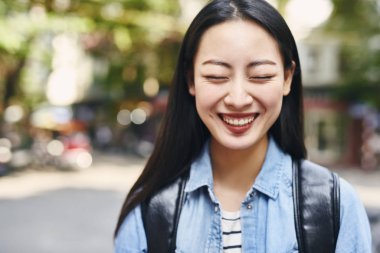 Şehirde sırt çantalı neşeli bir kadının portresi. 