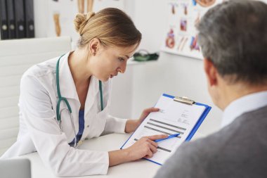 Doktor ve kıdemli adam panodaki sonuçlara bakıyor.