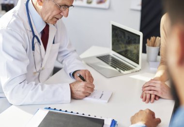 Doktor hastaları için reçete yazıyor.