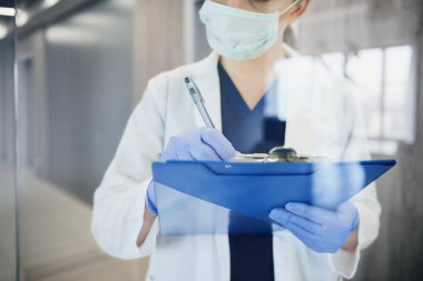 Yüz maskeli doktor tıbbi muayene yapıyor.