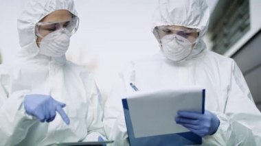 Elinde belge ve tabletle yürüyen iki teknisyenin videosu. 8K 'da kırmızı helyum kamerayla çekildi..