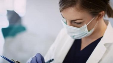 Yüz maskeli bir doktorun tıbbi muayene yaparken videosu.