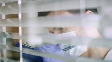 Pencerenin arkasından bakan bir doktor var. 8K 'da kırmızı helyum kamerayla çekildi..