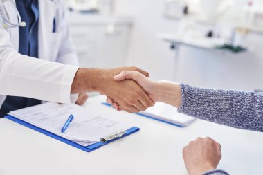 Doktor ve hastanın muayenehanesinde tokalaşma detayları.