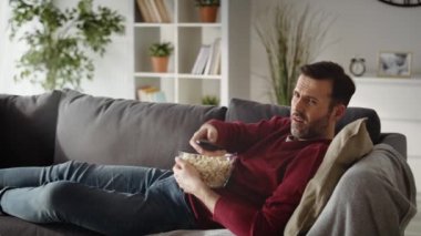 Evde televizyon izleyen sıkılmış bir adamın videosu. 8K 'da kırmızı helyum kamerayla çekildi..