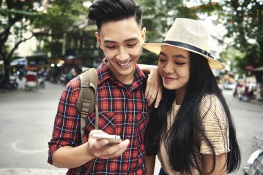 Seyahat ederken cep telefonu kullanan genç çift.