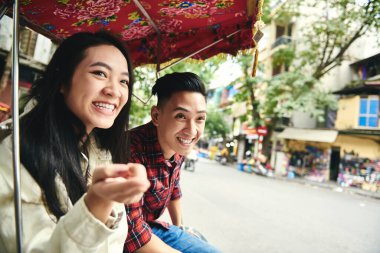 Vietnam triportörüyle seyahat eden ve bir şeyi işaret eden bir çift.