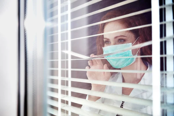 窓を通して見ている女性医師 — ストック写真