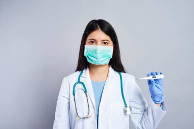 Doktor elinde bir termometre tutuyor. 