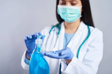 Kadın doktor el dezenfektanı kullanıyor.