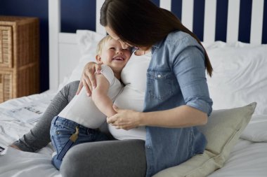 Anne ve tatlı çocuk yatakta birlikte oynuyorlar.
