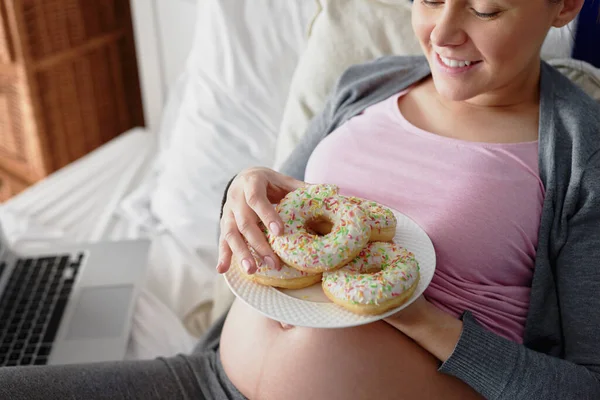 Těhotná Žena Jíst Barevné Koblihy Posteli — Stock fotografie