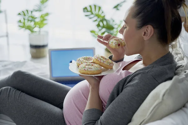 Ciężarna Kobieta Jedząca Pączki Przed Komputerem — Zdjęcie stockowe