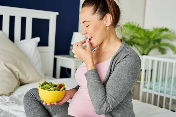 陽気妊娠中の女性果物のボウルを食べる — ストック写真