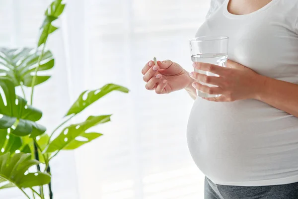 妊娠中の女性は錠剤を飲んで水を飲む — ストック写真