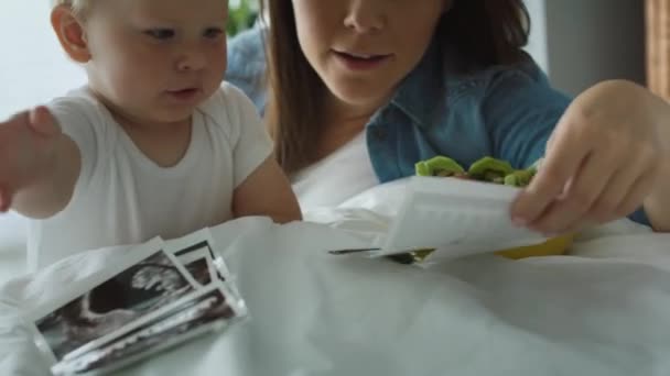 Kvinnan Och Hennes Son Bläddrar Bland Gravida Foton Sängen Skjuten — Stockvideo