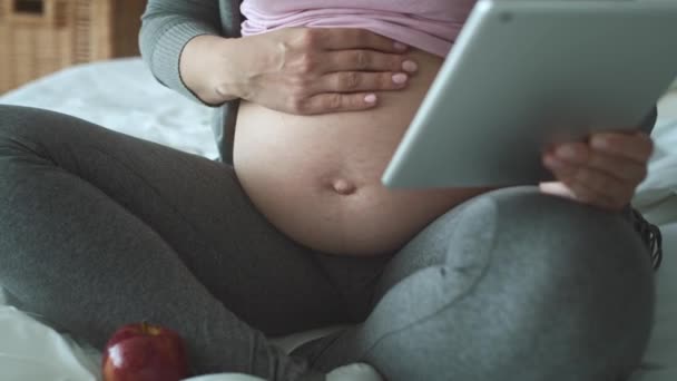 跟踪无法辨认的孕妇在床上使用平板电脑的左视频 用8K的红色氦相机拍摄 — 图库视频影像
