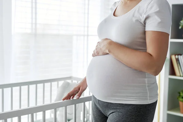 赤ん坊のベビーベッドの横に立つ妊婦 — ストック写真
