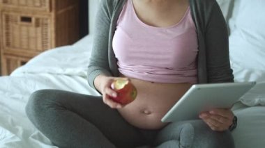 Hamile kadının yatakta tablet kullandığı videoyu izliyorum. 8K 'da kırmızı helyum kamerayla çekildi.  