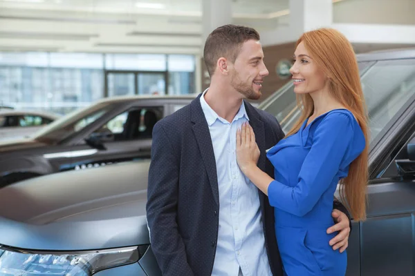 Jovem casal elegante comprar carro de luxo na concessionária — Fotografia de Stock