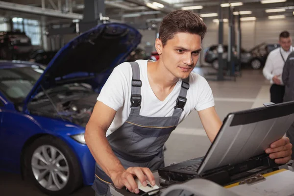 Joven mecánico de coches guapo reparación de vehículos en su garaje —  Fotos de Stock