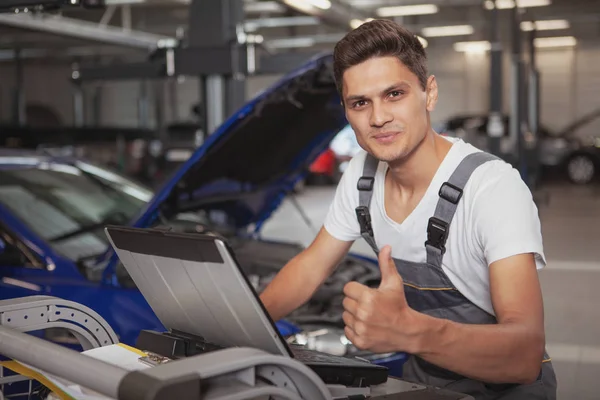 Młody przystojny mechanik samochodowy naprawy pojazdu w jego garażu — Zdjęcie stockowe