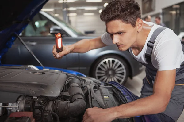 Joven mecánico de coches guapo reparación de vehículos en su garaje —  Fotos de Stock