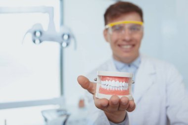 Kliniğinde çalışan yakışıklı erkek dişçi.