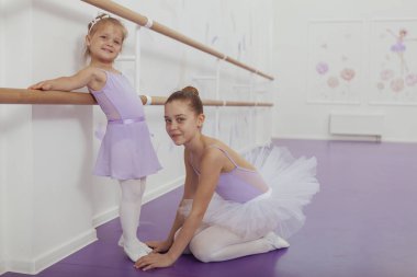 İki genç balerin bale dersinde pratik yapıyor.