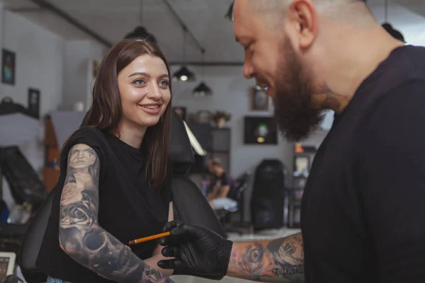 Молодая привлекательная женщина делает новую татуировку с помощью профессиональной татуировки — стоковое фото