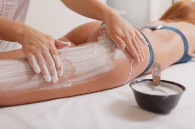 Çekici kadın spa merkezinde maskeyle vücut sargıları alıyor.