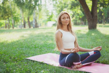 Parkta yoga yapan muhteşem atletik kadın.
