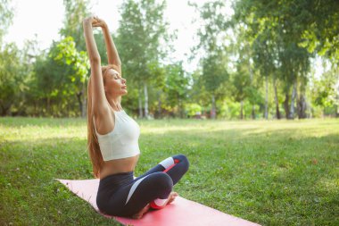 Parkta yoga yapan muhteşem atletik kadın.