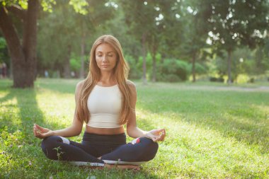 Parkta yoga yapan muhteşem atletik kadın.