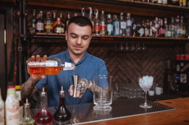 Yakışıklı erkek dövmeli barmen içki hazırlıyor.
