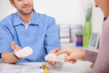 Bir hastaya göğüs implantı gösteren estetik cerrah