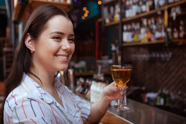 Charmante jonge vrouw genieten van een drankje aan de bar — Stockfoto