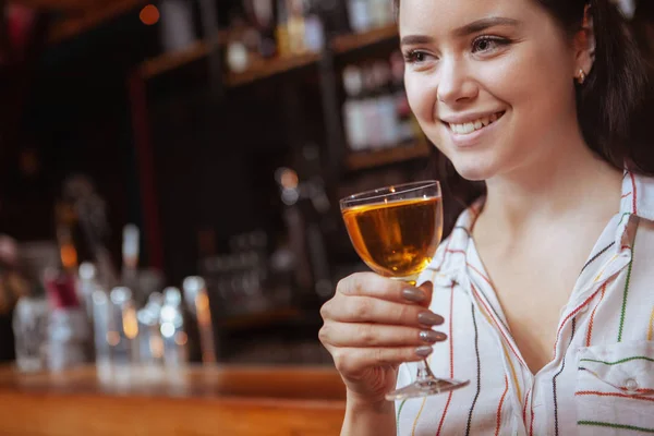 Charmante jonge vrouw genieten van een drankje aan de bar — Stockfoto