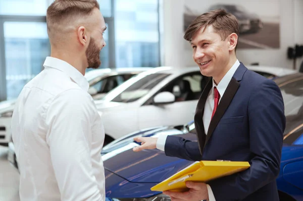 Hombre guapo comprando coche nuevo en el concesionario —  Fotos de Stock