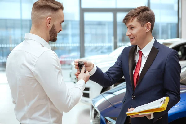 Hombre guapo comprando coche nuevo en el concesionario —  Fotos de Stock