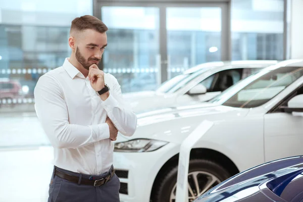 Красивий чоловік вибирає новий автомобіль у дилерському центрі — стокове фото