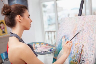 Sanat dersinde resim çizerken rahatlayan güzel bir genç bayanın fotoğrafını çek.