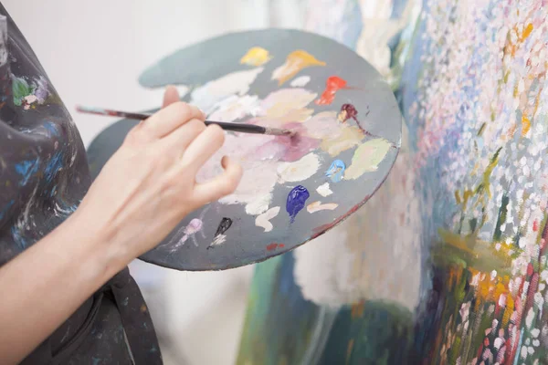 一个女画家在调色板上混合油画的特写 — 图库照片