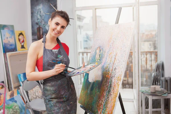 迷人而快乐的年轻女子在艺术工作室欣赏绘画 工作坊上兴高采烈的女画家绘画 — 图库照片