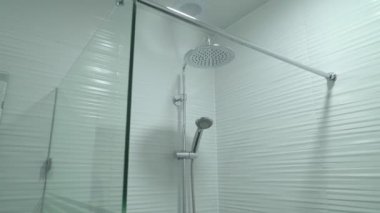 Duş kabini camdan yapılmış, duvarında el tutkalı yapıştırıcı asılı.