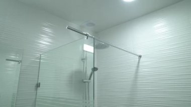 Duş kabini camdan yapılmış, duvarında el tutkalı yapıştırıcı asılı.