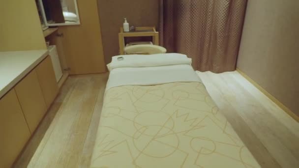 ヘッドサポートベッドとタオルカーテンと木製の床付きの暗いマッサージルーム — ストック動画