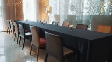 Masaları olan bir restoran, avizeleri ve büyük pencereleri olan parlak koltuklar.