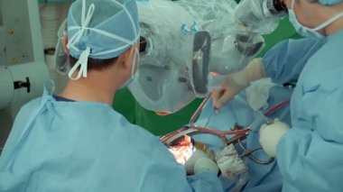 Cerrah ameliyathanede elektron mikroskobuyla insan kafatasını ameliyat eder.