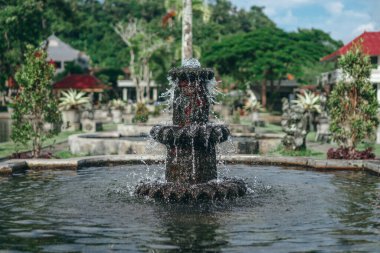 Suda duran eski bir Bali taş çeşmesinin fotoğrafı.